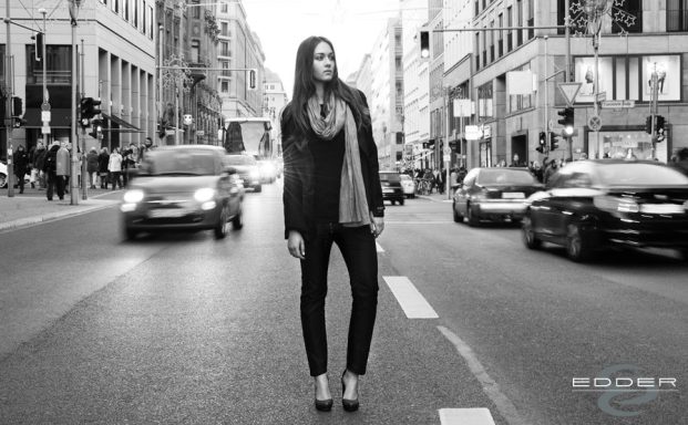 Urban Femme Fashion by umasan Frau in modischer Kleidung steht auf der Straße zwischen fahrenden Autos.